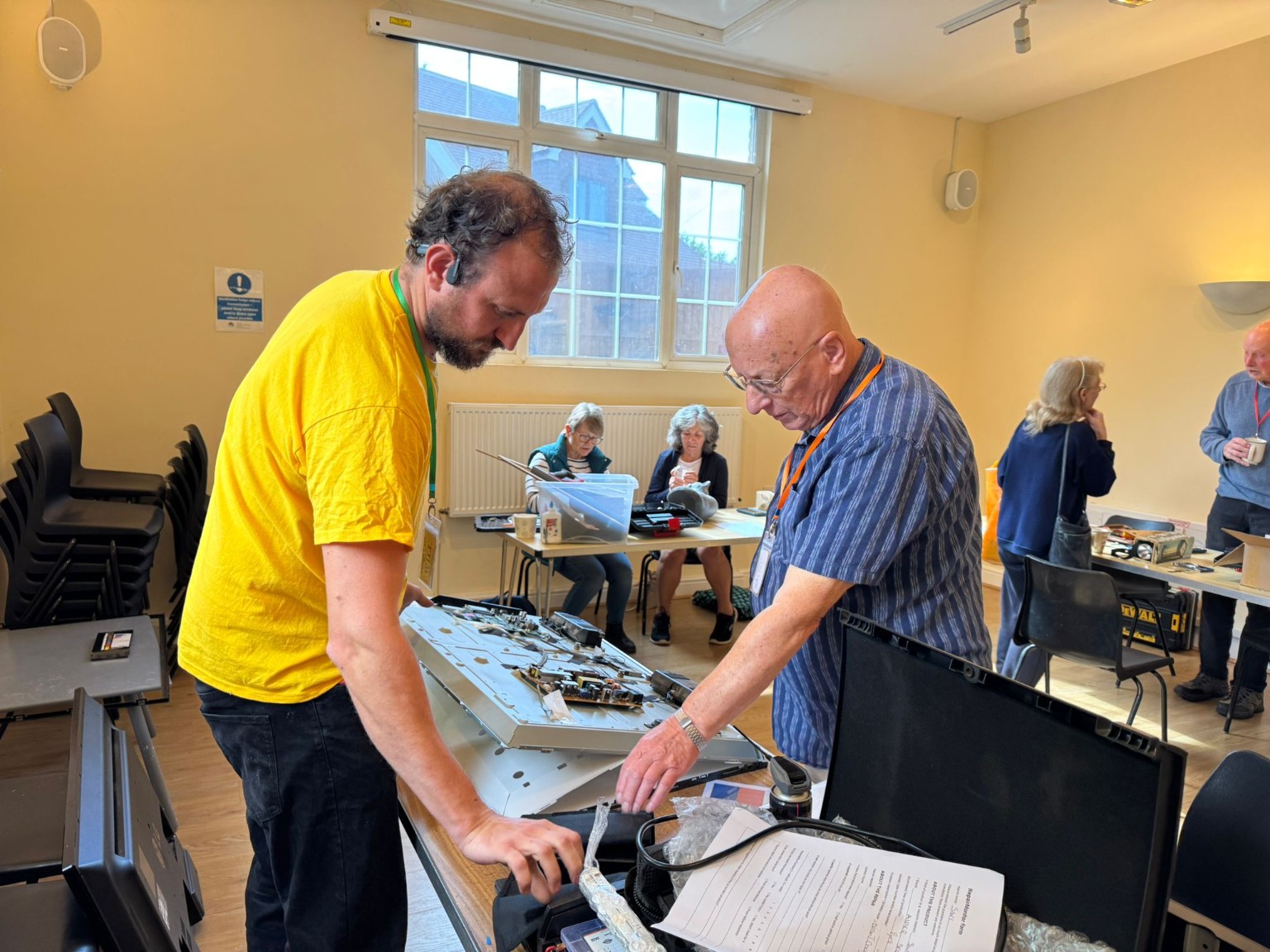 Volunteers working together to repair electronic equipment at a Repair Café Iver event