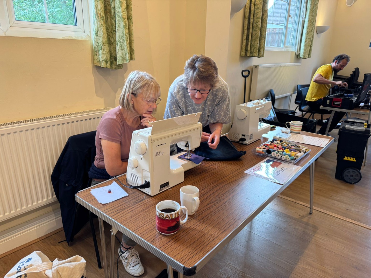 Visitors repairing textiles with sewing machines at a Repair Café Iver event